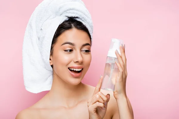 Glücklich schöne Frau mit Handtuch auf dem Haar und Reinigungsschaum isoliert auf rosa — Stockfoto