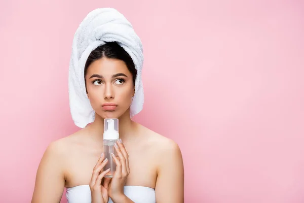 Bella donna pensosa con asciugamano su capelli e schiuma detergente isolata su rosa — Foto stock