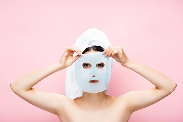 Belle femme avec une feuille de masque sur le visage isolé sur rose — Photo de stock