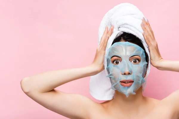 Schockierte schöne Frau mit Maske im Gesicht isoliert auf rosa — Stockfoto