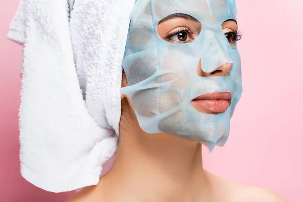 Belle femme avec une feuille de masque sur le visage isolé sur rose — Photo de stock