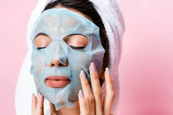 Belle femme avec une feuille de masque sur le visage isolé sur rose — Photo de stock