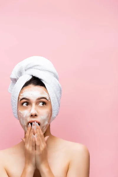 Beautiful woman with towel on hair and foam on face isolated on pink — Stock Photo