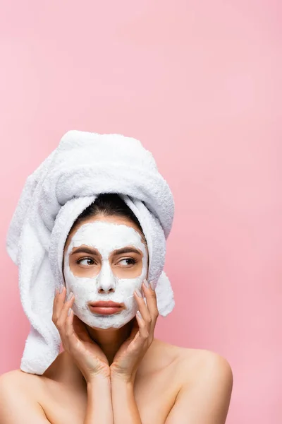 Sad beautiful woman with towel on head and clay mask on face isolated on pink — Stock Photo