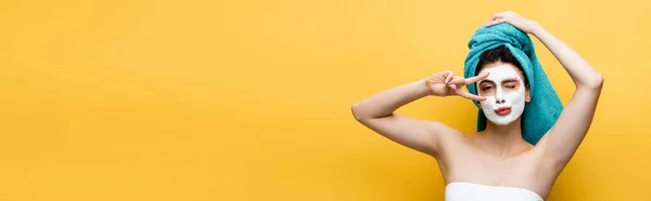 Bela mulher com toalha azul no cabelo e máscara de barro no rosto sorridente isolado no amarelo, banner — Fotografia de Stock