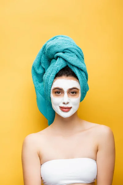 Bela mulher com toalha azul no cabelo e máscara de barro no rosto isolado no amarelo — Fotografia de Stock