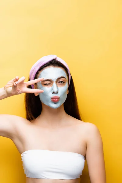 Belle femme avec masque en argile sur le visage grimacant isolé sur jaune — Photo de stock