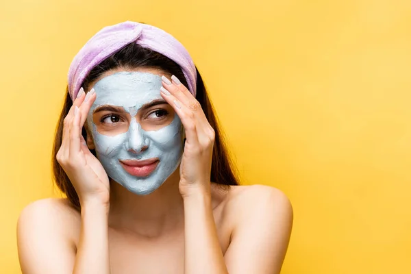 Schöne Frau mit Tonmaske im Gesicht isoliert auf gelb — Stockfoto