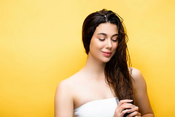 Smiling beautiful woman with wet hair isolated on yellow — Stock Photo