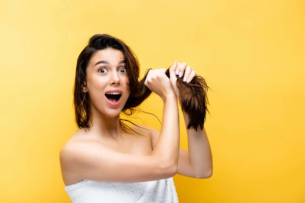 Schockierte schöne Frau mit nassen Haaren isoliert auf gelb — Stockfoto