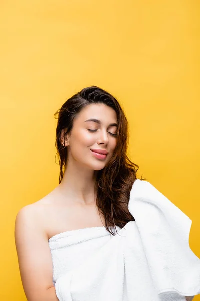 Bella donna sorridente con capelli bagnati e asciugamano isolato su giallo — Foto stock