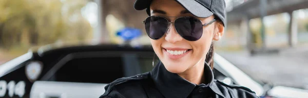 Ritratto di una poliziotta felice che guarda la macchina fotografica su sfondo sfocato all'aperto, banner — Foto stock