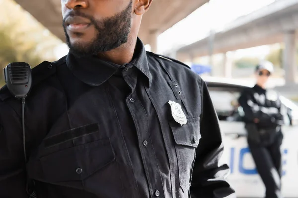 Close up view of african american policeman with radio set on blurred background outdoors — Stock Photo