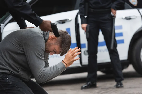 African american policeman aiming with gun at offender with blurred colleague on background outdoors — Stock Photo