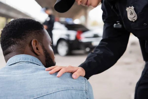 Policewoman apaisant victime afro-américaine dans la rue urbaine — Photo de stock