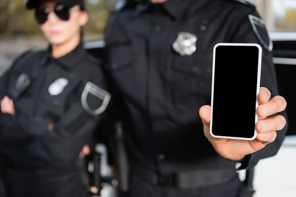 Smartphone with blank screen in hand of police officer near colleague on blurred background — Stock Photo