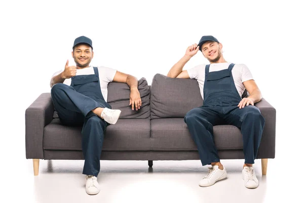 Full length of happy indian worker showing thumb up near mover sitting on couch on white — Stock Photo