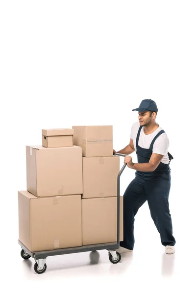 Volle Länge der indischen Mover in Overalls ziehen schwere Hand LKW mit Kartons auf weiß — Stockfoto