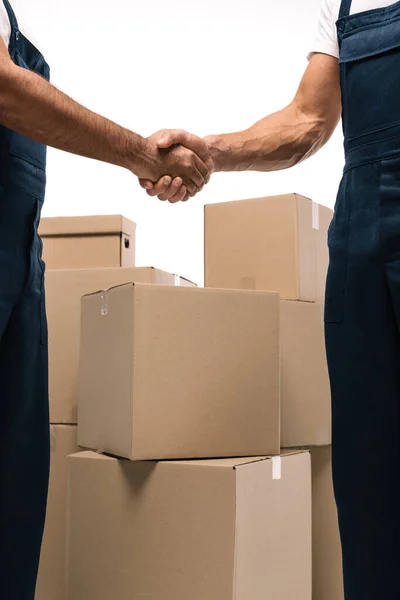 Cropped view of handymen shaking hands near boxes isolated on white — Stock Photo