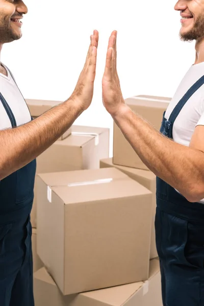 Vista recortada de trabajadores multiculturales felices dando alta cinco cajas cerca aislados en blanco — Stock Photo