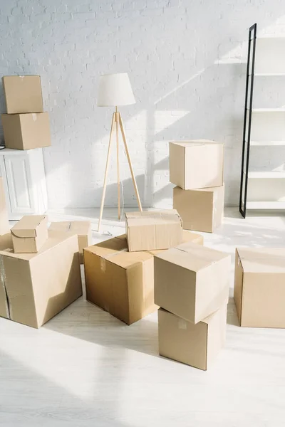 Pila de cajas de cartón cerca de lámpara de pie en apartamento moderno - foto de stock