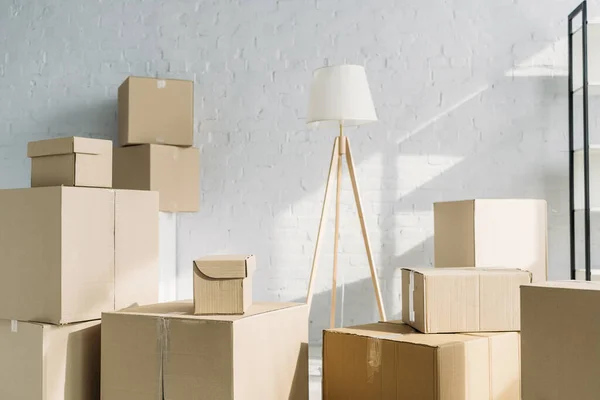 Pilha de caixas de papelão perto de lâmpada de assoalho no apartamento moderno — Fotografia de Stock