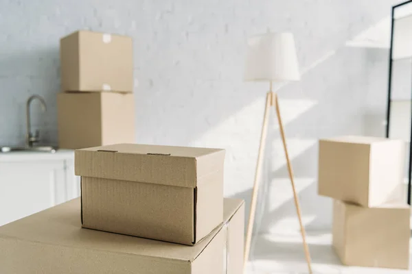 Carton boxes near floor lamp on blurred background — Stock Photo