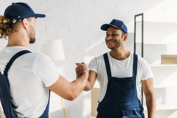 Glückliche multiethnische Arbeiter beim Händeschütteln in der Wohnung — Stockfoto