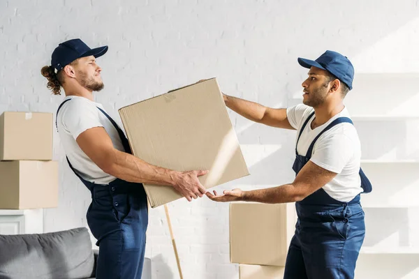 Young worker in uniform passing carton box to indian coworker — Stock Photo