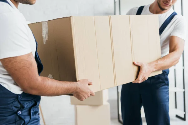 Vue partielle des déménageurs multiethniques tenant la boîte en carton — Photo de stock