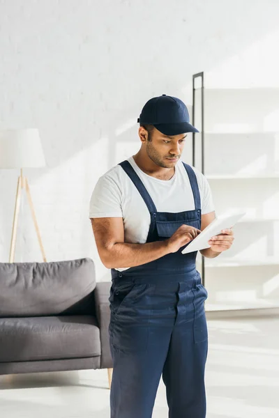 Indischer Arbeiter in Uniform nutzt digitales Tablet in Wohnung — Stockfoto