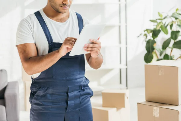 Cropped view of indian worker in uniform using digital tablet in apartment — Stock Photo