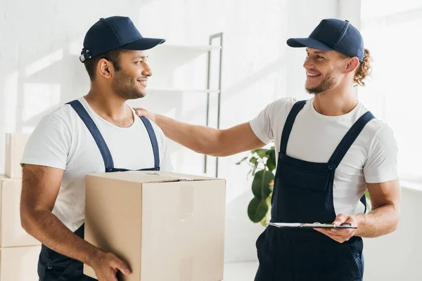 Fröhliche multikulturelle Macher lächeln, während sie sich in der Wohnung anschauen — Stockfoto