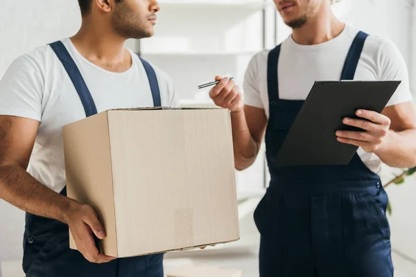 Cropped view of multicultural movers holding boxes in apartment — Stock Photo