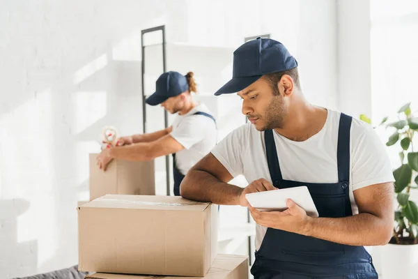 Indischer Mover hält digitales Tablet in der Nähe von Mitarbeiter auf verschwommenem Hintergrund — Stockfoto