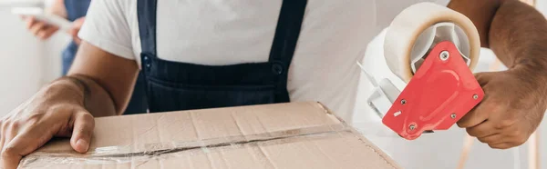 Partial view of man holding scotch tape while packing box — Stock Photo