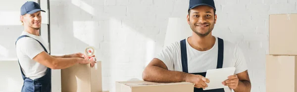 Sorridente movimento indiano che tiene tablet digitale vicino al collega su sfondo sfocato, banner — Foto stock