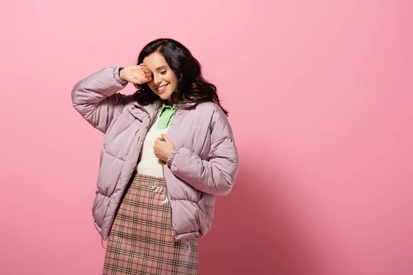 Smiling brunette young woman in stylish winter outfit posing on pink background — Stock Photo