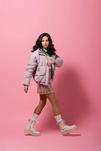 Side view of brunette young woman in stylish winter outfit on pink background — Stock Photo