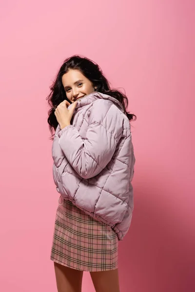 Улыбающаяся брюнетка в пиджаке, позирующая на розовом фоне — стоковое фото