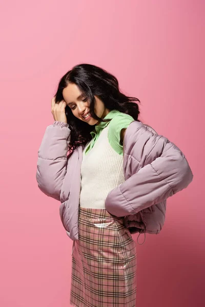 Sorrindo morena jovem mulher em roupa de inverno em fundo rosa — Fotografia de Stock