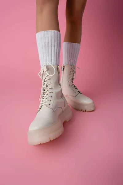 Vista cortada de pernas femininas em botas e meias no fundo rosa — Fotografia de Stock
