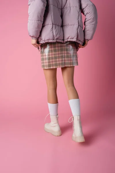Rückansicht einer jungen Frau in stylischem Winteroutfit auf rosa Hintergrund — Stockfoto
