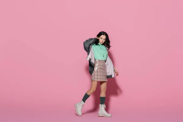 Morena mujer joven en traje casual de invierno posando sobre fondo rosa - foto de stock