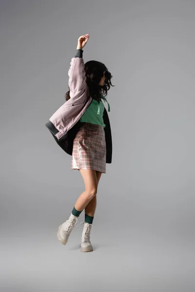 Morena mujer joven en elegante traje de invierno posando sobre fondo gris - foto de stock