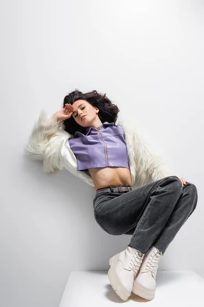 Top view of elegant brunette young woman in stylish faux fur jacket posing on white background — Stock Photo