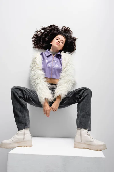 Vista dall'alto di elegante bruna giovane donna in pelliccia sintetica giacca in posa su sfondo bianco — Foto stock