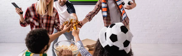 Fanáticos del fútbol multiétnico tintineo botellas de cerveza, pancarta - foto de stock