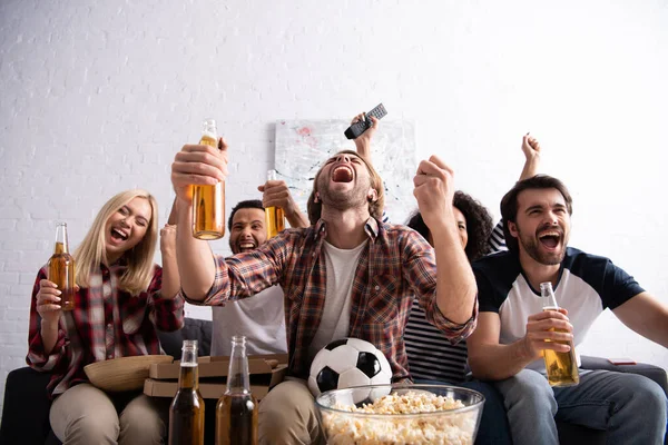 Excited multiethnic friends screaming and showing win gesture while watching football championship — Stock Photo