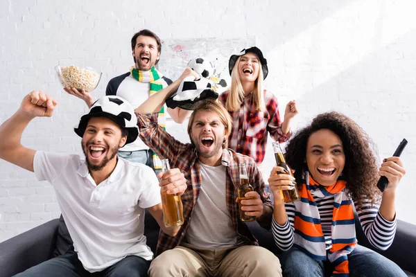 Excités amis multiethniques montrant geste de victoire tout en regardant le championnat de football à la maison — Photo de stock